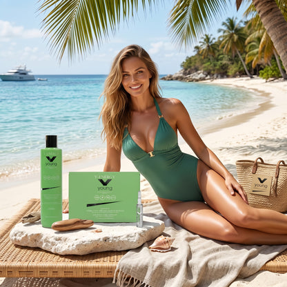 John Hair Y-Energy anti-hair loss set with shampoo and vials on a beach with a woman in a green swimsuit