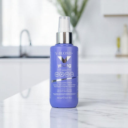 John Hair Young Y-Blond+ purple leave-in toning spray for blonde hair in a 150ml bottle on a marble counter.